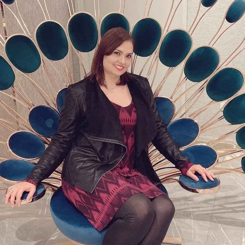 Gabriela Brum seated in a blue velvet peacock chair